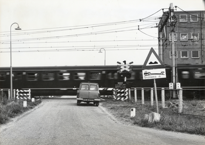 169451 Gezicht op de spoorwegovergang in de Vlierweg / Odijkseweg te Houten, met een passerende trein.